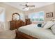 A primary bedroom featuring plantation shutters, a ceiling fan, and wood furnishings at 19712 N Bridge Ct, Maricopa, AZ 85138