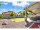 Open backyard with a patio, lush grass, trees, and a sturdy block wall at 25776 N Sandstone Way, Surprise, AZ 85387