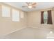 A bedroom featuring a ceiling fan, beige walls, carpet flooring, and three windows at 25776 N Sandstone Way, Surprise, AZ 85387
