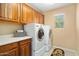 Laundry room with side-by-side washer and dryer, wood cabinets, a window, and neutral walls at 25776 N Sandstone Way, Surprise, AZ 85387