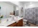 Bright bathroom with double sinks, wood cabinets, and a shower-tub combination behind a patterned curtain at 37236 N Navarra Rd, San Tan Valley, AZ 85140