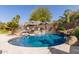 Resort-style pool features rock features, palm trees, umbrella, and beautiful blue water at 502 E Kona Dr, Casa Grande, AZ 85122