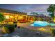 Backyard with pool, lounge chairs, covered patio, lush landscaping, and evening lighting at 631 W Stanley Ave, San Tan Valley, AZ 85140