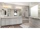 Bright bathroom features a double vanity with granite countertop, grey tile flooring, and glass-enclosed shower at 631 W Stanley Ave, San Tan Valley, AZ 85140