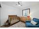 Bright bedroom with ceiling fan, wood floors, a crib, dresser and comfortable blue chair at 7102 W Wilshire Dr, Phoenix, AZ 85035