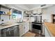 Bright kitchen with stainless steel appliances, butcher block countertops, and open shelving at 7102 W Wilshire Dr, Phoenix, AZ 85035