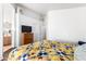 Bright bedroom with a colorful quilt, view of the ensuite bathroom, and a dresser with a TV at 7336 S 253Rd Ave, Buckeye, AZ 85326