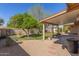 Backyard featuring a covered patio, green grass, decorative trees, and a gravel area at 9022 N 39Th Ave, Phoenix, AZ 85051