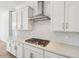 Close-up of a gourmet kitchen with white cabinets, backsplash, and stainless steel range hood at 11447 E Utah Ave, Mesa, AZ 85212