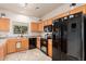 Well-lit kitchen with wooden cabinets, black appliances, and modern backsplash at 13212 W Lisbon Ln, Surprise, AZ 85379