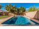 A stunning backyard pool with a cascading water feature, surrounded by mature trees and desert landscaping for added privacy at 13212 W Lisbon Ln, Surprise, AZ 85379