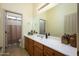 This bathroom features neutral tile, a large vanity, and a door to a separate toilet and shower area at 14124 W Christy Dr, Surprise, AZ 85379