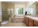 This bathroom features neutral tile, a shower, a tub, a window with blinds, and a single sink vanity at 14124 W Christy Dr, Surprise, AZ 85379