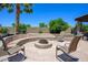 Outdoor fire pit surrounded by a stone bench and chairs on a stone patio, perfect for entertaining or relaxing at 14124 W Christy Dr, Surprise, AZ 85379