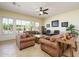 Spacious living room featuring leather furniture, a ceiling fan, and large windows offering views of the pool at 14124 W Christy Dr, Surprise, AZ 85379