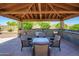 Covered outdoor kitchen features a grill, stainless steel appliances, bar seating, and a dining table with chairs at 14124 W Christy Dr, Surprise, AZ 85379