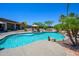 Backyard pool area featuring a freeform pool, stone accents, mature trees, and lounge chairs for relaxation at 14124 W Christy Dr, Surprise, AZ 85379