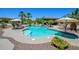 Resort-style pool features a covered seating area, lounge chairs, tropical landscaping, and a beautiful rock waterfall feature at 14124 W Christy Dr, Surprise, AZ 85379