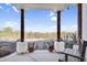 Covered patio with decorative wooden columns, concrete flooring, and a desert view showcasing native vegetation at 1550 W Adobe Dam Dr, San Tan Valley, AZ 85144