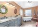 Bathroom featuring double sinks, granite countertops, decorative mirrors, modern lighting, and a clawfoot bathtub at 15620 N 19Th St, Phoenix, AZ 85022