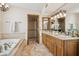 Luxurious bathroom showcasing a double sink vanity with granite countertops and a jetted tub with decorative tile surround at 16611 E Inca Ave, Fountain Hills, AZ 85268