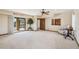 Spacious living room featuring plush carpeting, a ceiling fan, and sliding glass doors to the outdoor pool area at 16611 E Inca Ave, Fountain Hills, AZ 85268