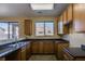 This kitchen features oak cabinets, black countertops, stainless steel sink, and natural lighting at 17025 W Rimrock St, Surprise, AZ 85388