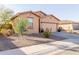 View of a well-maintained tan home featuring a two-car garage and desert landscaping at 18842 N Lariat Rd, Maricopa, AZ 85138