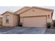 Tan colored home featuring a two car garage, desert landscaping, and a front window at 18842 N Lariat Rd, Maricopa, AZ 85138