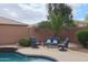 Relaxing poolside seating area with cozy chairs, complemented by a lush garden and a towering palm at 2509 E Dulcinea Trl, Casa Grande, AZ 85194