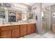 Well-lit bathroom with double sinks, wood cabinets, decorative mirrors, and tiled walk-in shower at 2712 S Tambor --, Mesa, AZ 85209