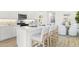 Kitchen island featuring a sink, stainless steel appliances, white cabinets, quartz countertops, and barstool seating at 27288 N 74Th Ln, Peoria, AZ 85383