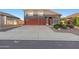 Exterior view showcasing a gray home with a red tile roof, three-car garage, and manicured landscaping at 31446 N Candlewood Dr, San Tan Valley, AZ 85143