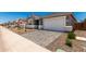 View of the two-car garage, gray exterior, stone facade, brick paver driveway, and desert landscaping at 40531 W Michaels Dr, Maricopa, AZ 85138