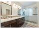 Bathroom featuring double vanity, and glass shower with beautiful stone flooring at 44383 W Windrose Dr, Maricopa, AZ 85138