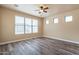 Large bedroom featuring a ceiling fan, wood-look flooring, and large windows at 44383 W Windrose Dr, Maricopa, AZ 85138