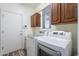 Bright laundry room featuring dark wood cabinets, LG washer and dryer and a door for privacy at 44383 W Windrose Dr, Maricopa, AZ 85138