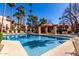 A community pool features clear blue water and a tiled pool house surrounded by lounge chairs and palm trees at 9355 N 91St St # 113, Scottsdale, AZ 85258