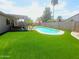 Enjoy the sun in this backyard featuring an artificial lawn, pool and covered patio at 9654 N 94Th Ave, Peoria, AZ 85345