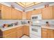 Bright kitchen features light wood cabinets, a white range and microwave, and ample counter space at 11069 E Kilarea Ave # 198, Mesa, AZ 85209