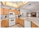 Well-lit kitchen features white appliances, light wood cabinets, and a breakfast bar open to the living room at 11069 E Kilarea Ave # 198, Mesa, AZ 85209