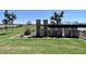 A landscaped community entrance with stone pillars, metal design elements, and lush green grass providing an inviting view at 11426 E Utopia Ave, Mesa, AZ 85212