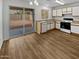 Bright kitchen featuring white cabinets, wood-look flooring, and a sliding glass door to the backyard at 11734 W Paradise Dr, El Mirage, AZ 85335