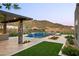 Inviting backyard features an outdoor kitchen, pool with waterfall, and desert landscape at 14102 E Sonora Crest Dr, Fountain Hills, AZ 85268