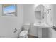 This bathroom is equipped with a pedestal sink, toilet, and a round mirror on the wall at 14628 W Sand Hills Rd, Surprise, AZ 85387