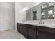 Bathroom with dual sinks, dark wood cabinets, and a large mirror at 15822 W Bronco Trl, Surprise, AZ 85387