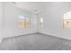 A spacious bedroom with large windows offering plenty of natural light and plush gray carpeting at 15822 W Bronco Trl, Surprise, AZ 85387