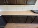 Close-up of a kitchen featuring dark cabinets, light countertops, white subway tile, and stainless-steel fixtures at 17032 W Fetlock Trl, Surprise, AZ 85387