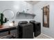 Modern laundry room with black washer and dryer, a shelf with supplies, and a decorative laundry sign at 18069 W Tina Ln, Surprise, AZ 85387