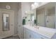 Bathroom with double doors, white vanity with ample counter space, shower, and decorative mirror with plenty of light at 18187 W Via Montoya Dr, Surprise, AZ 85387